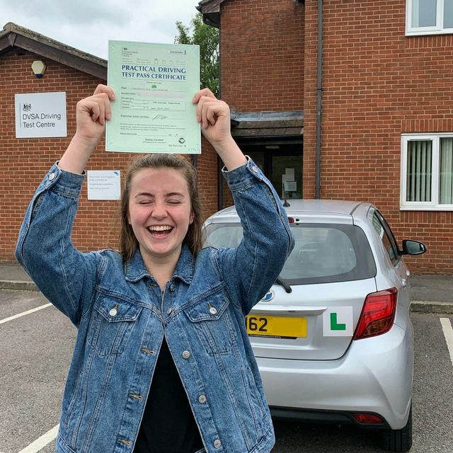 Happy person holding a driving test pass certificate